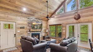 A log cabin interior with a fireplace, leather sofas, and a stone wall. - Antler Ridge 3 Bedroom Cabin by RedAwning (Sevierville)
