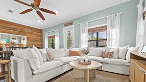 Ein Wohnzimmer mit einem Ecksofa, einem runden Couchtisch und einem Deckenventilator.