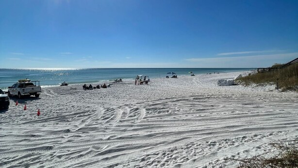 Ein Strand mit einem weißen Pickup und mehreren Strandsonnenschirmen.