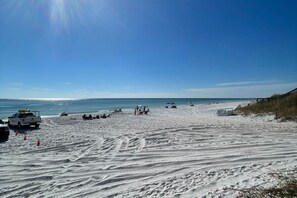 A beach with a white pickup truck and several beach umbrellas. - Sundaze 4 Bedroom Home by RedAwning (Santa Rosa Beach)