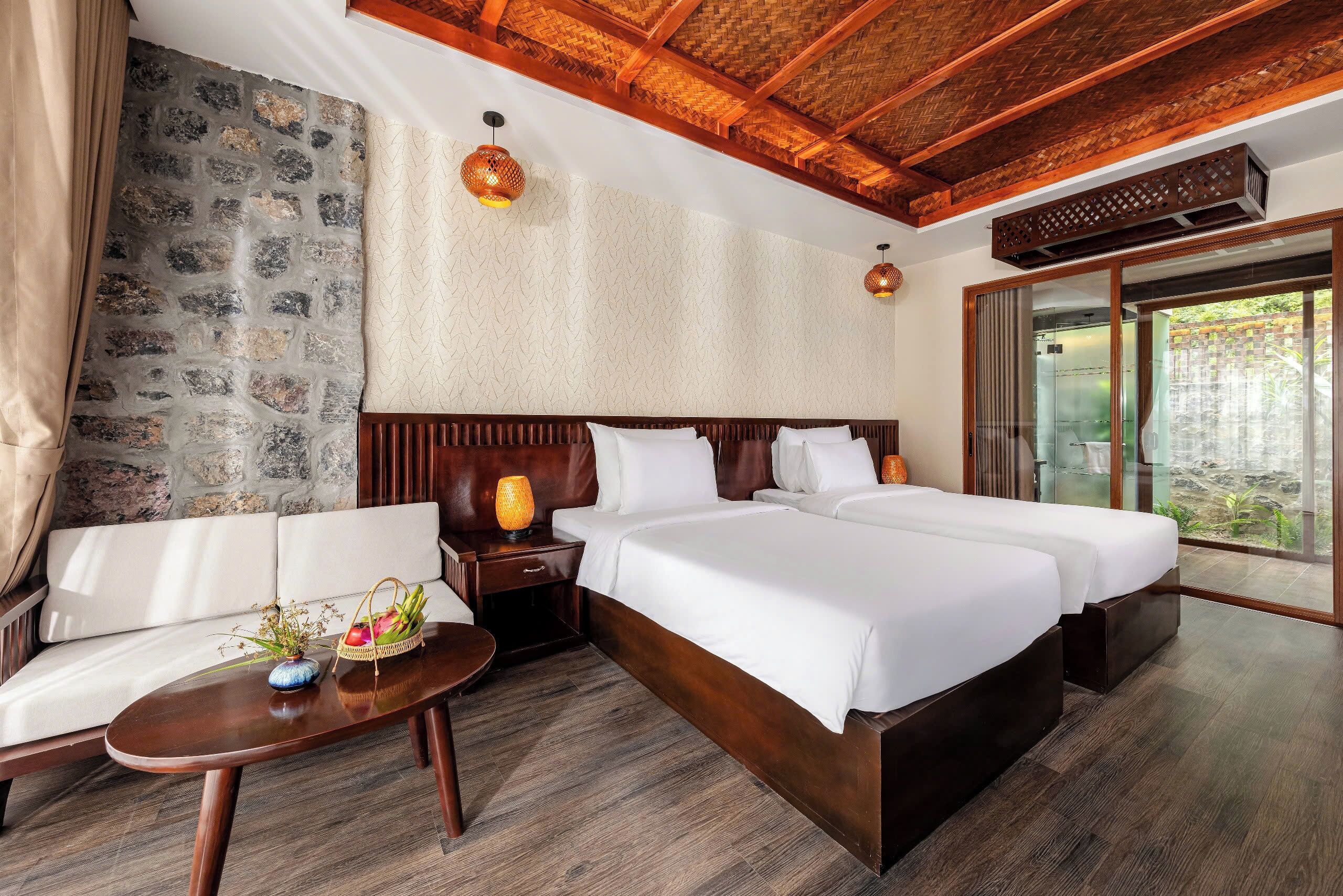 Une chambre d’hôtel avec un mur en pierre, un plafond en bois et un grand lit.