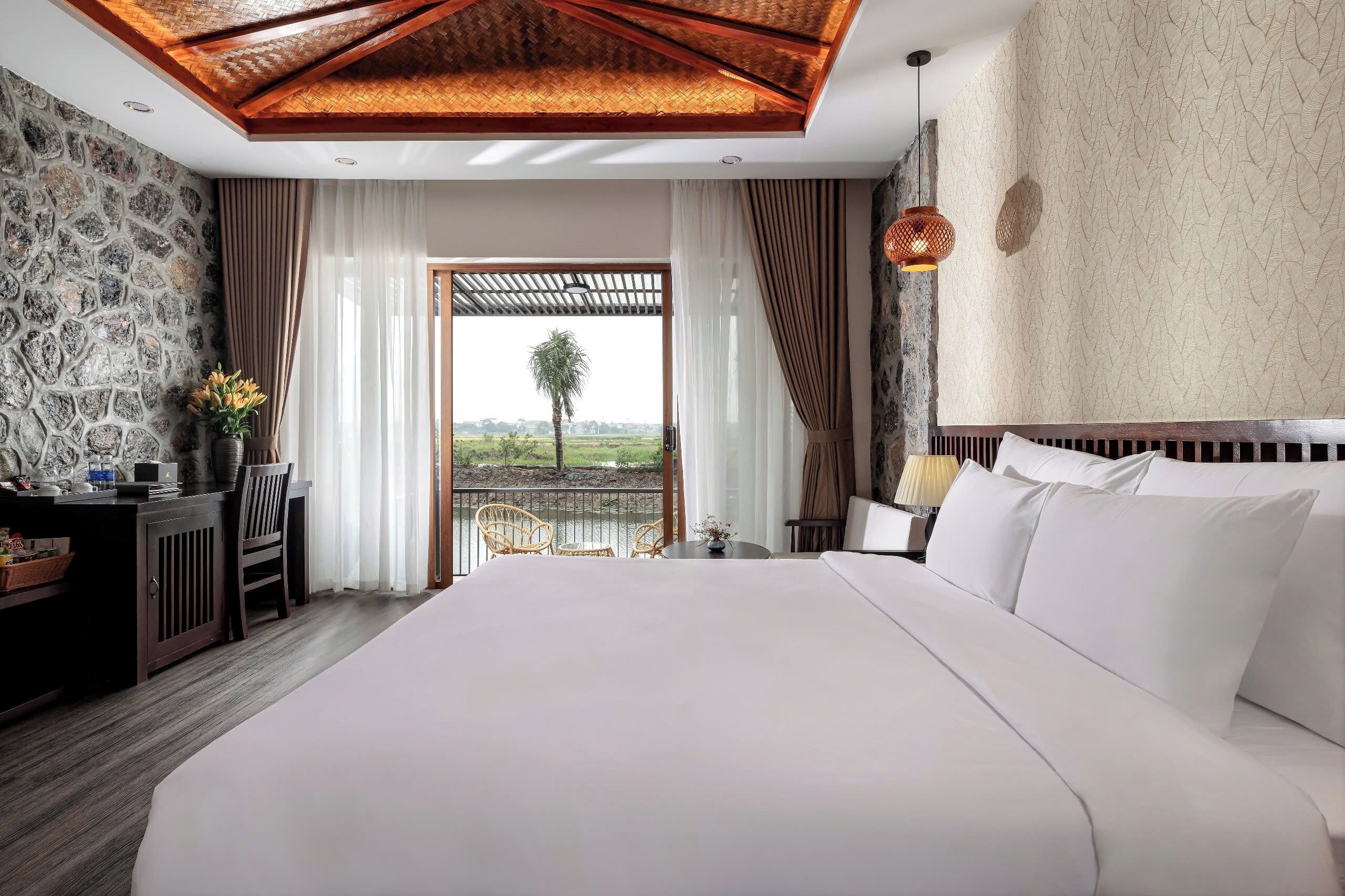 A spacious bedroom with a large bed, a desk with a chair, and a view of the outdoors.