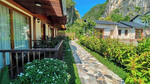 A pathway leading to a building with a wooden roof and a balcony. - Athena Premier Resort Ninh Bình (Nam Hoa Lu)