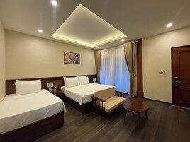 Una habitación de hotel con dos camas, un sofá, una mesita y un cuadro en la pared, además de una puerta con pomo.