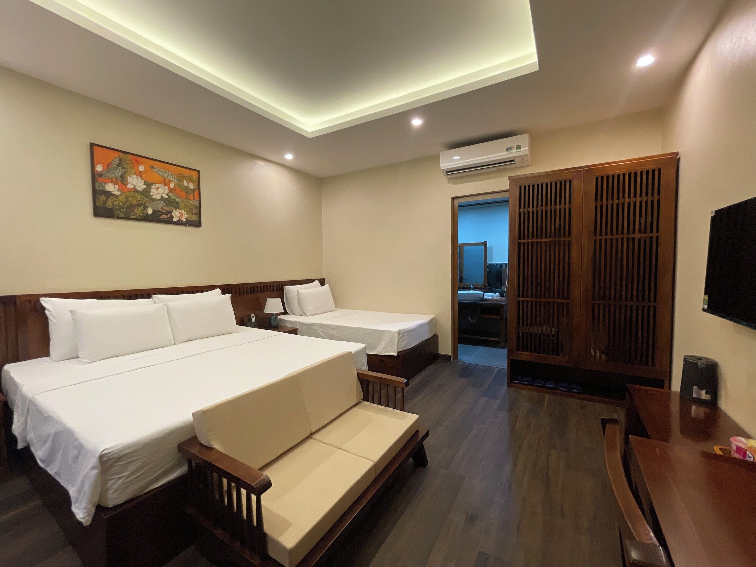 A hotel room with two beds, a sofa, a desk, and a TV.