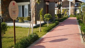 A resort with a stone facade, a red pathway, and a sign listing room numbers and amenities. - Spree Resort Sariska (Thanagazi)
