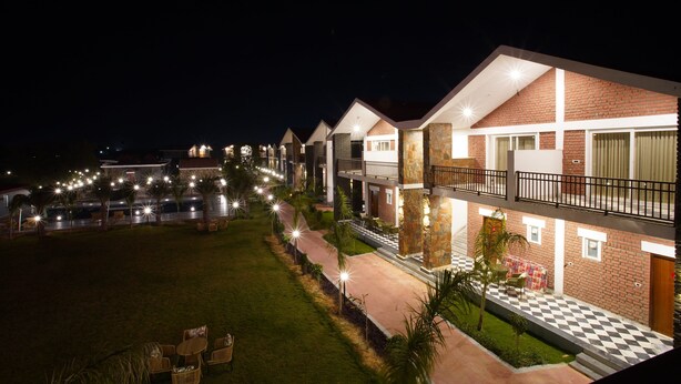 A hotel with multiple floors, outdoor seating, and a well-lit pathway. - Spree Resort Sariska (Thanagazi)