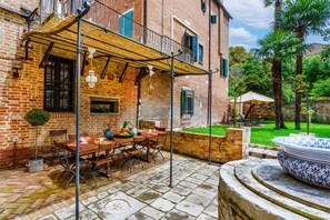 Une terrasse avec une table et des chaises, un luminaire suspendu et un vase décoratif.