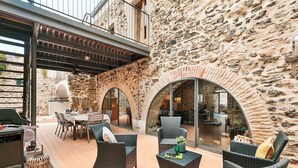 An outdoor patio with wicker furniture, a grill, and stone walls. - Garriguella- Roses – Pool Costa Brava House (Garriguella)