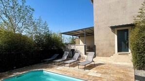 En pool med liggestole, en moderne bygning og en klar blå himmel.