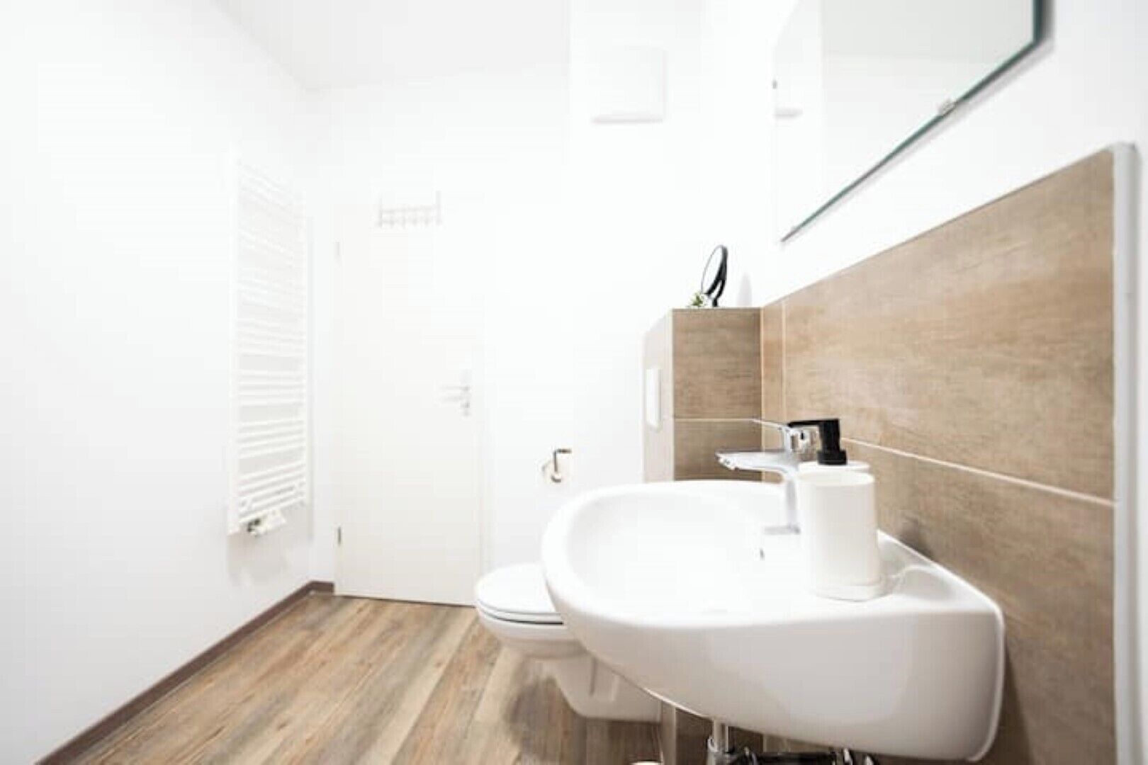 A modern bathroom with a white sink, toilet, and shower.