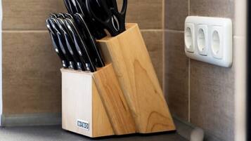 A kitchen corner with a wooden knife block holding various knives and scissors, a power outlet, and a tiled backsplash.