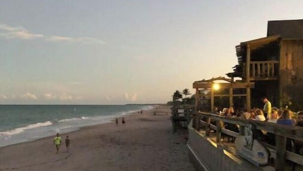A beachside restaurant with outdoor seating overlooking the ocean.