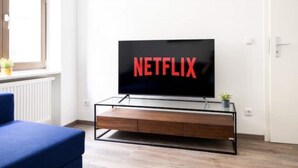 A modern living room with a television displaying the Netflix logo, a blue sofa, and a wooden entertainment unit.