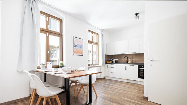 A modern kitchen with white cabinets, a wooden countertop, and a black faucet.