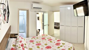 Een slaapkamer met een bed, een kledingkast, een airconditioning en een televisie.