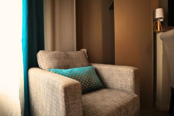 Cozy corner with a comfortable armchair and patterned cushion, paired with a floor lamp.