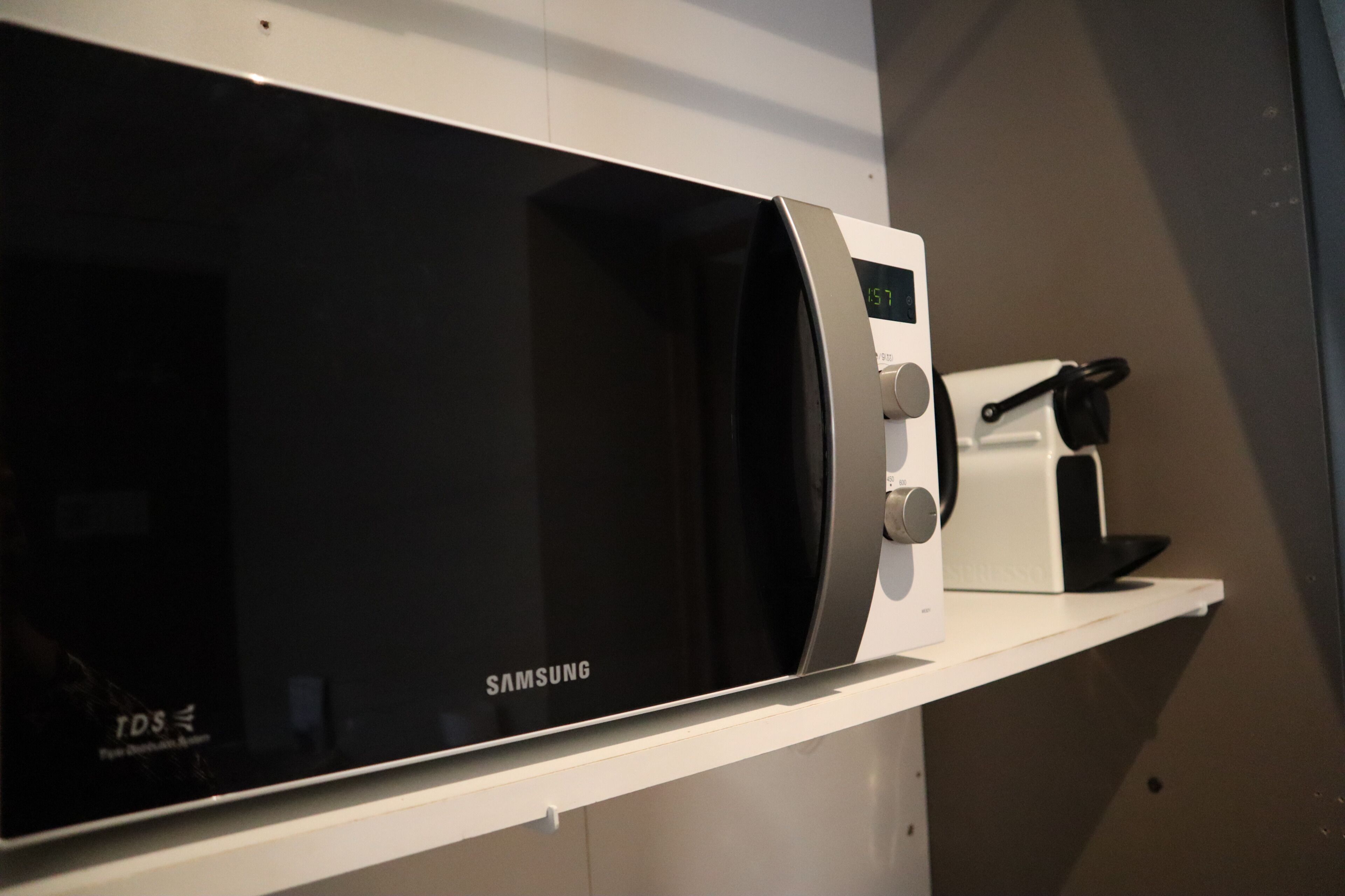 A Samsung microwave on a white shelf.