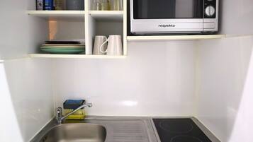 Una cocina compacta con un fregadero, estufa y microondas.