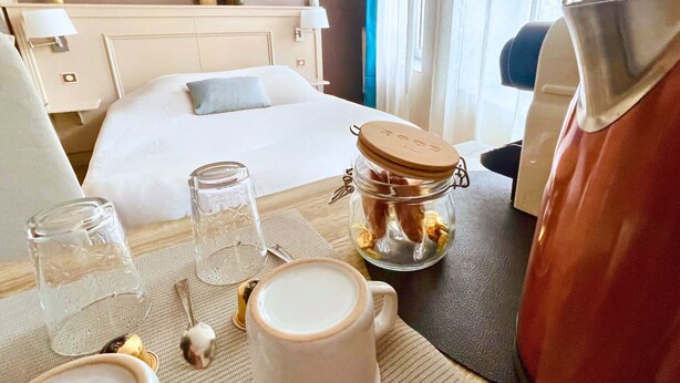 A hotel room with a bed, a bedside table with a glass jar, a cup, and a spoon. - Le Gîte des Voyageurs  (Bourbourg)