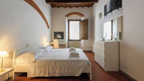A bedroom with a bed, bedside lamps, a dresser, and a window with a view. - Borgo Art Apartment by Mmega (Florence)