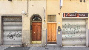 A building with a closed wooden door, a metal shutter door with graffiti, and a sign for 'L'ANTICO BORGO'. - Borgo Art Apartment by Mmega (Florence)