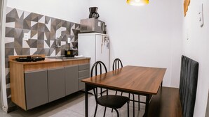 Una cocina compacta con encimera de madera, microondas integrado y zona de comedor con mesa y sillas de madera.