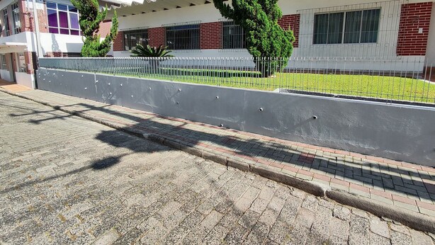 Un edificio de diseño moderno, con techo plano, fachada de ladrillo y valla de metal.