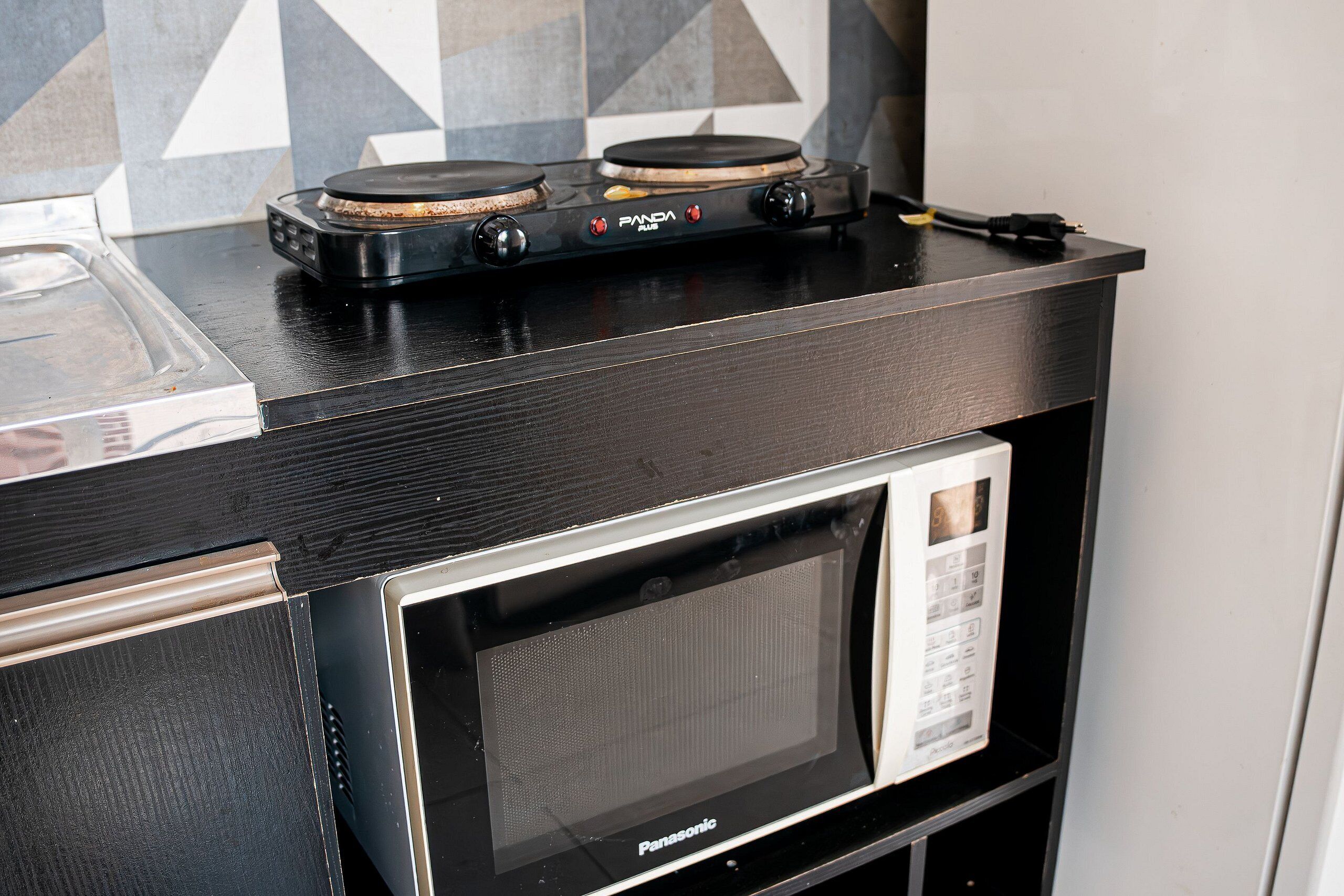 A kitchen with a black countertop, a microwave, and a stove with a control panel.