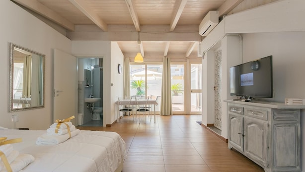 A hotel room with a bed, a TV, a desk with a chair, and a bathroom visible through an open door. - Terrazza Corallo by Wonderful Italy (Bari)