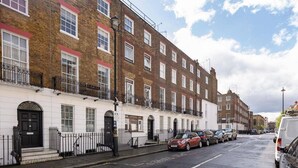 A row of terraced houses with a white facade and red brick upper floors. - Prime Central London Private Studio Apartment (London)