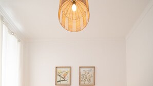 A bedroom with a bed, two bedside lamps, a hanging light fixture, and two framed botanical prints on the wall. - SibsSanlucar Duquesa - Ideal Parejas (Sanlúcar de Barrameda)