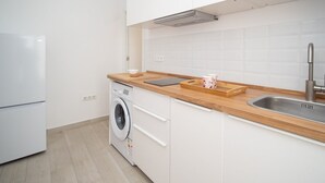 A modern kitchen with white cabinets, a wooden countertop, a built-in washing machine, and a stainless steel sink. - SibsSanlucar Duquesa - Ideal Parejas (Sanlúcar de Barrameda)
