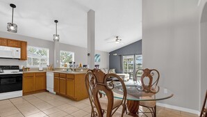 Una cocina moderna con armarios de madera, una mesa de comedor de vidrio y un ventilador de techo.