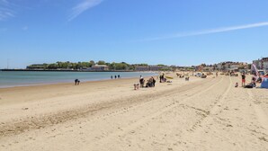 A wide sandy beach with a clear sky and calm sea. - Day Cottage (Weymouth)