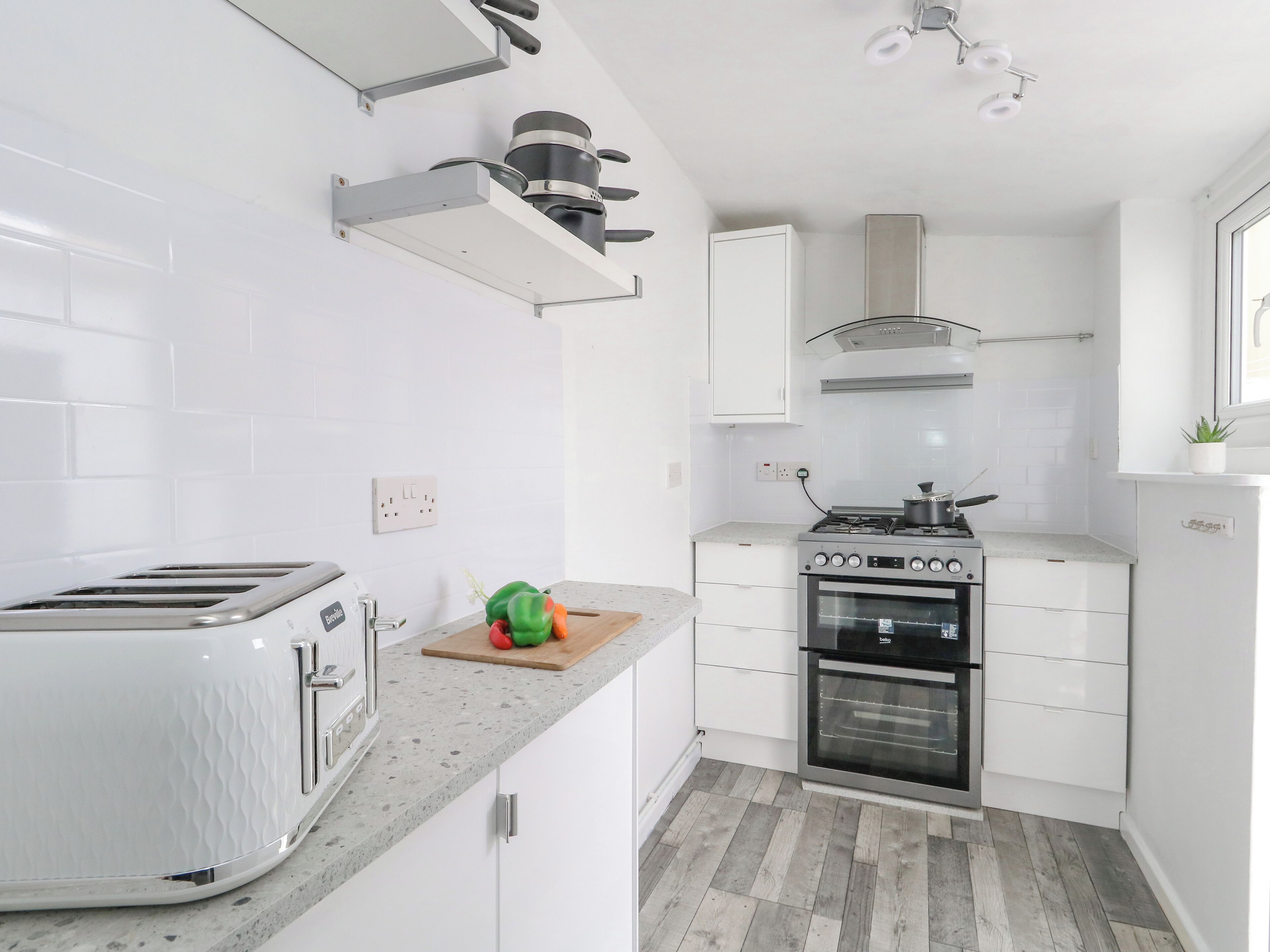 A modern kitchen with white cabinets, a built-in oven, a gas stove, and a toaster.