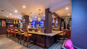Un espace bar doté d’un long comptoir, de nombreux tabourets et d’un bar bien garni de bouteilles.