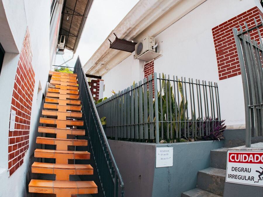 Un escalier menant à un bâtiment entouré d’une clôture métallique et sur lequel est apposée une pancarte indiquant que les marches ne sont pas uniformes.