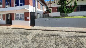 Un edificio de dos pisos con techo plano, entrada porticada y camino de entrada pavimentado.