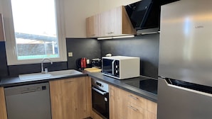 Een moderne keuken met houten kastjes, een roestvrijstalen koelkast, een magnetron en een vaatwasser.
