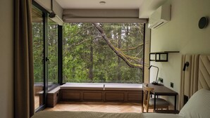 Un dormitorio con un ventanal grande, una cama, un escritorio y una silla.