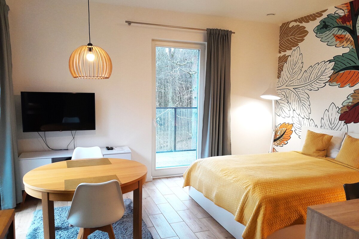 Une chambre à coucher comprenant un lit, un bureau, une chaise, un téléviseur et une fenêtre avec des rideaux.
