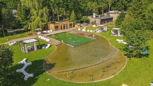 Vista aérea de un resort con piscina, áreas de descanso y una estructura tipo cabaña de madera.