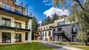 Un edificio residencial moderno con varios balcones, ventanas amplias y un césped bien cuidado.