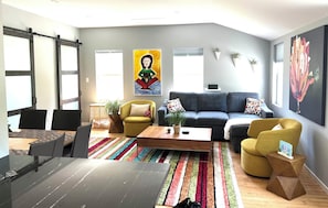 Una sala de estar moderna con sofá, sillones, una mesa de centro y un comedor con sillas y una mesa.