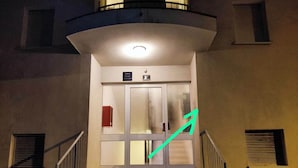 En byggnadsentré med en trappa som leder upp till en dörr som är märkt med "9A" och har texten "Apartman" ovanför.