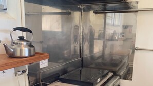 Een keuken met roestvrijstalen apparatuur, inclusief een gasfornuis, waterkoker en een werkblad van roestvrij staal.