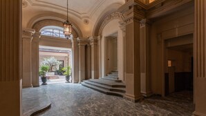 A grand hallway with marble flooring, classical columns, and a staircase leading to an upper level. - Casa Vel Apartment by Wonderful Italy (Turin)