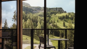 Una habitación con un amplio ventanal que ofrece vistas a un paisaje montañoso con árboles y cielo despejado.