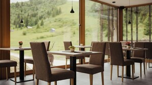 Un comedor moderno con amplios ventanales, mesas y sillas de madera.